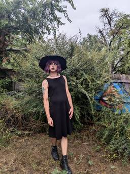 A transfemme goth baddie in their homemade black jersey dress